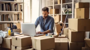 man working on a laptop surrounded by cardboard boxes
