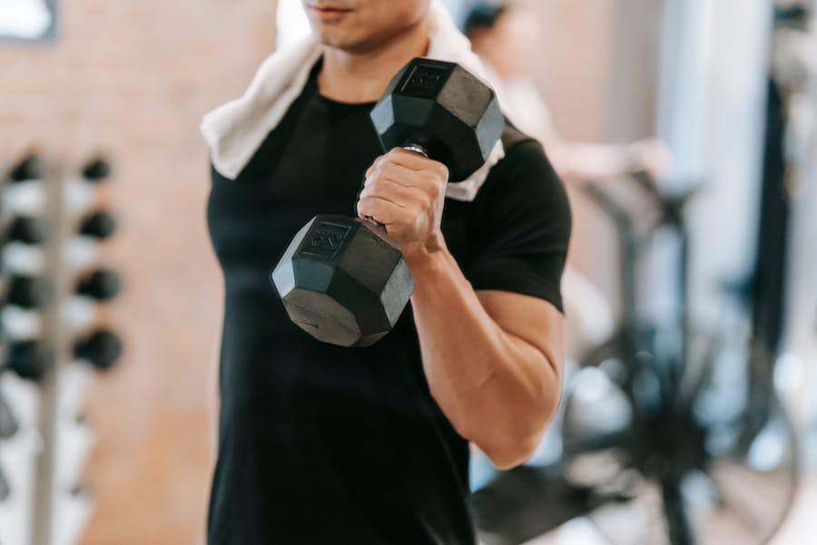 A man lifting a black dumbbell in a gym setting